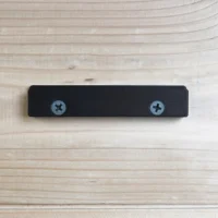 Black wall mount with two screw holes, designed to hold a track saw guide rail square vertically on a workbench or cabinet