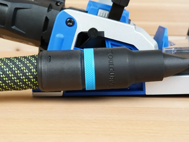 Black hose adapter with cyan band attached to Kreg Rebel pocket hole joiner dust port, connected to green and yellow braided hose