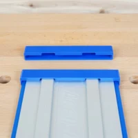Two blue PETG protective caps for Kreg Accu-Cut guide rails, one installed on a rail showing interior channels, one separate above