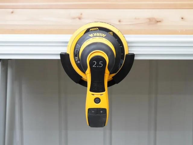 Yellow and black Mirka sander mounted in a holder attached to an aluminum MFT/3 rail, showing 2.5 marking on the sander head