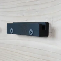 Dark blue wall mount with two Phillips screw holes, mounted horizontally on light wood