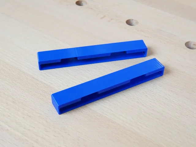 Two blue PETG protective caps with hollow channels, designed to slide onto the ends of Kreg Accu-Cut track saw rails