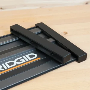 Two black PETG protective end caps slid onto the end of a Ridgid track saw guide rail on a wood bench