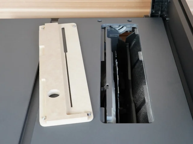 White MDF zero clearance insert next to its rectangular opening in a SKIL table saw top, showing mounting holes and dust port.