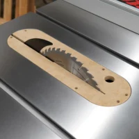 MDF zero clearance insert seated in a SawStop table saw, blade raised through the narrow kerf slot