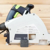 Black textured arbor dust cover snapped onto the side of a Festool TS 60 KEB track saw, side view