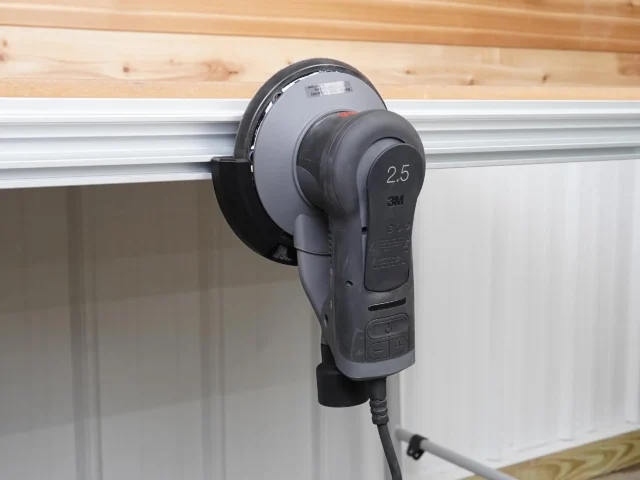 Black sander holder in an MFT/3 side T-track, cradling a gray 3M Xtract 2.5 orbital sander pad-out