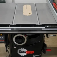 Light wood zero clearance insert with central slot mounted on SawStop table saw, showing top view with adjustment holes