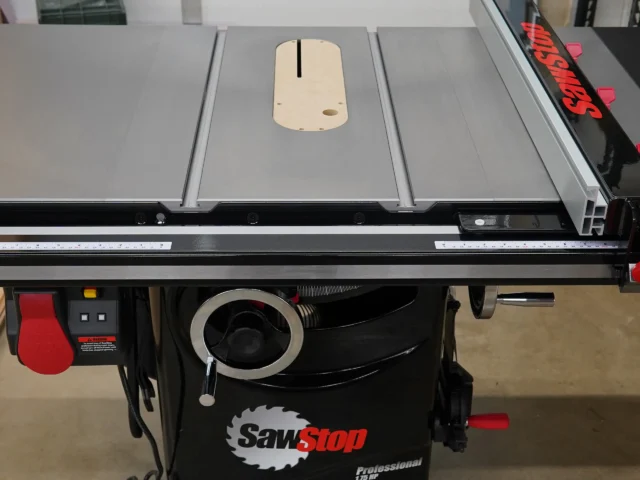 Light wood zero clearance insert with central slot mounted on SawStop table saw, showing top view with adjustment holes