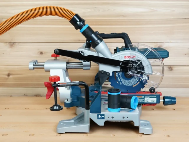 Black 1-1/4" hose adapter with blue bands joining an orange vacuum hose to a Bosch 18v miter saw dust port