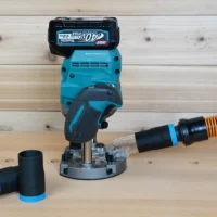 Black 1-1/4 inch hose adapter with blue band linking an orange hose to a Makita 40v XGT plunge router, second adapter beside it