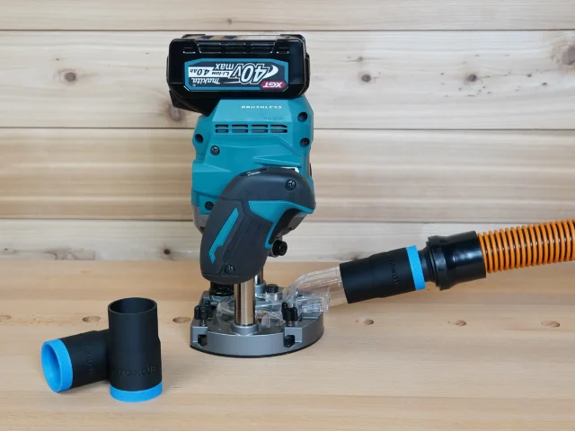 Black 1-1/4 inch hose adapter with blue band linking an orange hose to a Makita 40v XGT plunge router, second adapter beside it