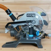 Black 1-1/4 inch hose adapter with blue collar on a Ryobi 10-inch miter saw dust port, orange hose attached