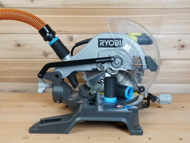 Black 1-1/4 inch hose adapter with blue collar on a Ryobi 10-inch miter saw dust port, orange hose attached