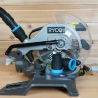 Black 1-7/8 inch hose adapter with blue trim on a Ryobi 10-inch miter saw dust port, hose attached