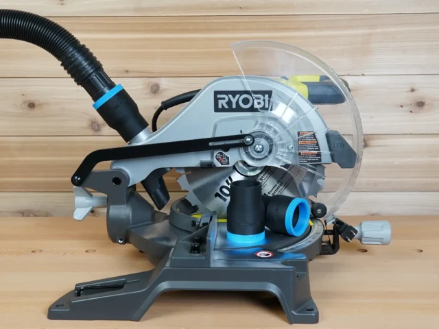 Black 1-7/8 inch hose adapter with blue trim on a Ryobi 10-inch miter saw dust port, hose attached