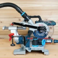 Black and blue ToolCurve 1-7/8 inch hose adapter joining a vacuum hose to a Bosch 18v miter saw dust port, with a second adapter resting on the saw base