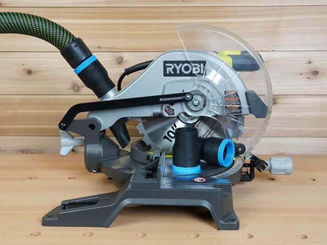 Black 36mm ToolCurve hose adapter with blue collar fitted to the dust port of a Ryobi 10-inch miter saw