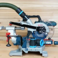 Black 36mm hose adapter with blue accents on a Bosch 18v miter saw dust port, extractor hose attached, second adapter resting on the base