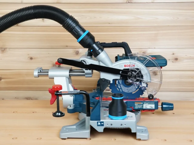 Black 2-1/2 inch hose adapter with blue band linking a ribbed vacuum hose to a Bosch 18v miter saw dust port