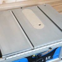 Zero clearance insert mounted on Kobalt 10" table saw, showing rounded cutout for blade with two mounting holes and offset adjustment screws