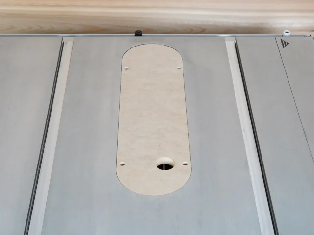 Dado zero clearance MDF insert seated flush in a Kobalt 10-inch table saw top, uncut with four leveling screw holes