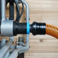 Black ToolCurve 1-1/4 inch hose adapter with blue band joining an orange shop vac hose to a Kobalt table saw dust port