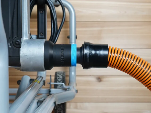Black ToolCurve 1-1/4 inch hose adapter with blue band joining an orange shop vac hose to a Kobalt table saw dust port