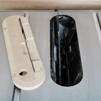 Zero clearance insert for Kobalt 10″ table saw shown in natural and black variants, displayed on a track with metal rails.