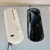 Cream-colored zero clearance insert next to black standard insert for Kobalt 10" table saw, both shown from above