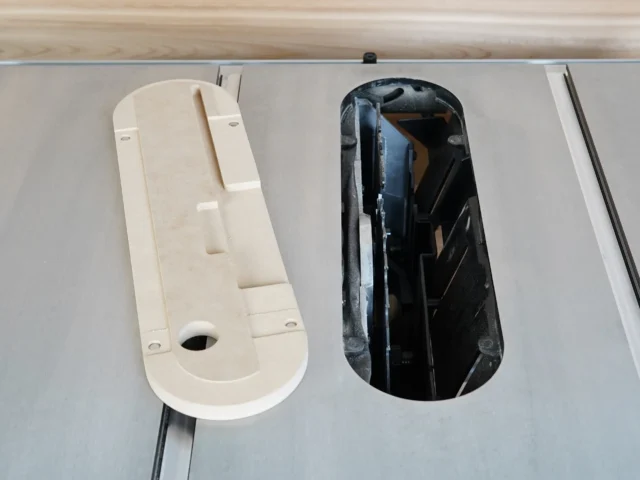 Cream-colored zero clearance insert next to black standard insert for Kobalt 10" table saw, both shown from above