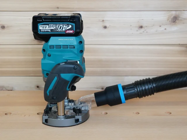 Black 1-7/8 inch hose adapter with blue band joining a vacuum hose to a Makita 40v XGT plunge router dust port