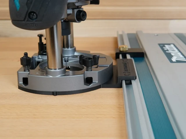 Guide Rail Adapter for Makita router mounted on a Makita track saw, showing the gray aluminum base plate clamped to the rail with the router positioned above