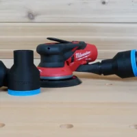 Black ToolCurve 2-1/2 inch hose adapters with blue rings beside a Milwaukee M12 sander, one joined to a vac hose