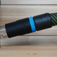 Black hose adapter with blue band attached to green braided hose, showing Makita branding on cylindrical body