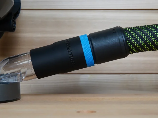 Black hose adapter with blue band attached to green braided hose, showing Makita branding on cylindrical body