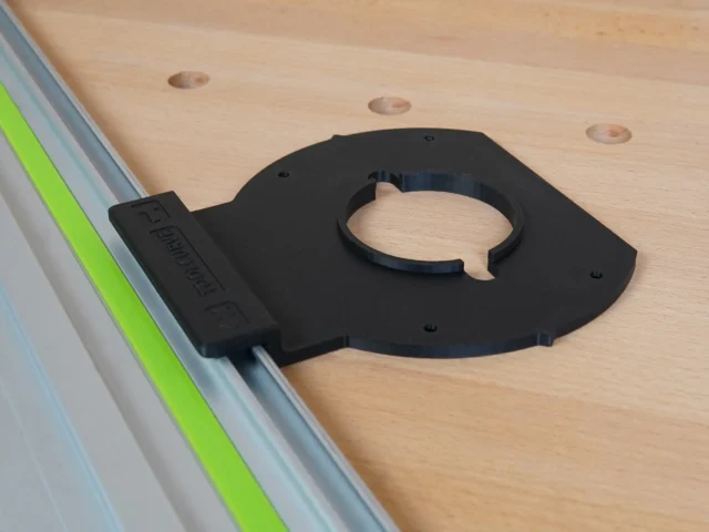 Black adapter mounted on Festool-style guide rail, with circular ring opening for router attachment and mounting holes visible