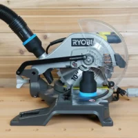 Black 2-1/2 inch ToolCurve hose adapter with blue band on a Ryobi 10-inch miter saw dust port, hose attached
