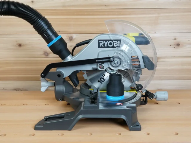 Black 2-1/2 inch ToolCurve hose adapter with blue band on a Ryobi 10-inch miter saw dust port, hose attached