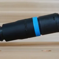 Black hose adapter with blue band attached to Milwaukee sander dust port, showing threaded connection and braided hose on right