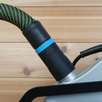 Black hose adapter with blue band attached to Ryobi compound miter saw dust port, with green and yellow braided hose connected above