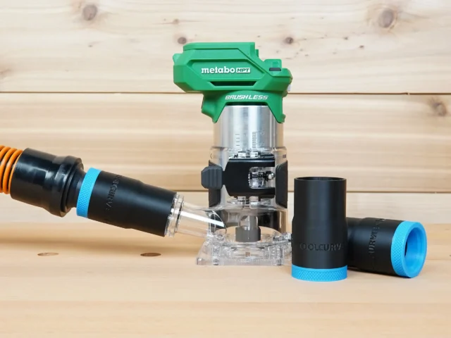 Black 1-1/4 inch hose adapter with blue collar joining an orange vac hose to a Metabo HPT trim router, with two spare adapters