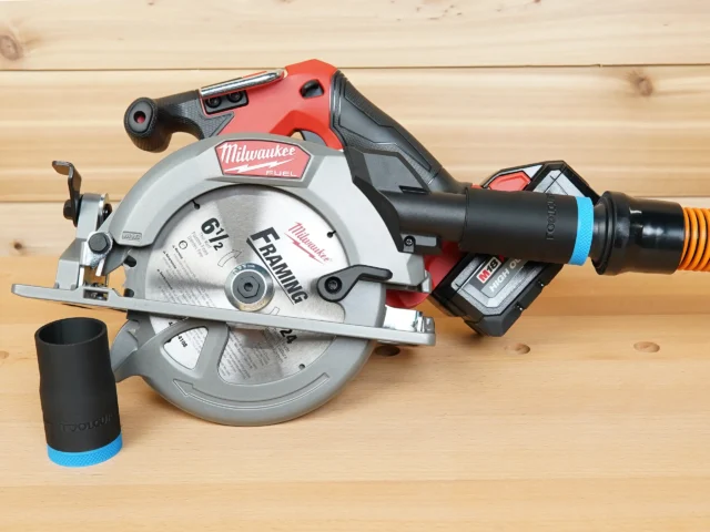 Black 1-1/4 inch hose adapter with blue band installed on a Milwaukee M18 circular saw dust port, second adapter beside it