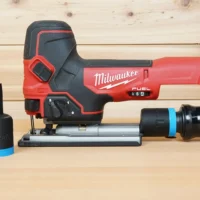 Black 1-1/4 inch ToolCurve hose adapter with blue band, shown alone and fitted to a Milwaukee M18 Fuel jig saw