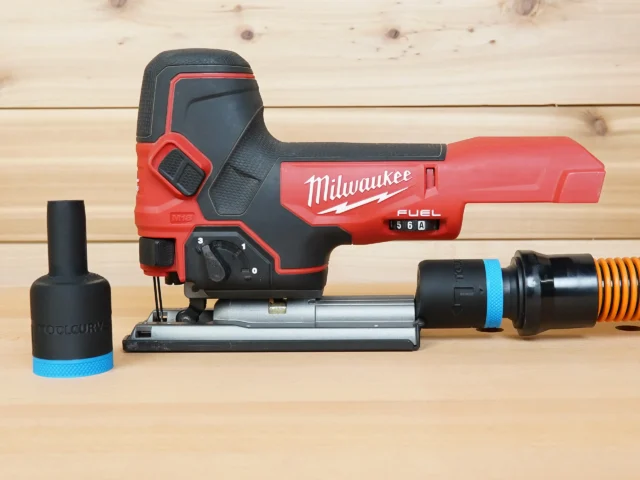 Black 1-1/4 inch ToolCurve hose adapter with blue band, shown alone and fitted to a Milwaukee M18 Fuel jig saw