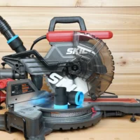 Black ToolCurve 1-7/8 inch hose adapters with blue rings resting on a SKIL 10 inch miter saw table, hose connected