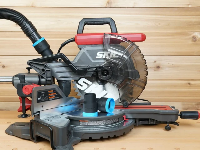 Black ToolCurve 1-7/8 inch hose adapters with blue rings resting on a SKIL 10 inch miter saw table, hose connected