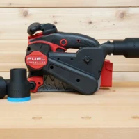 Black ToolCurve 1-7/8 inch hose adapter with blue band on a Milwaukee M18 belt sander, second adapter beside it