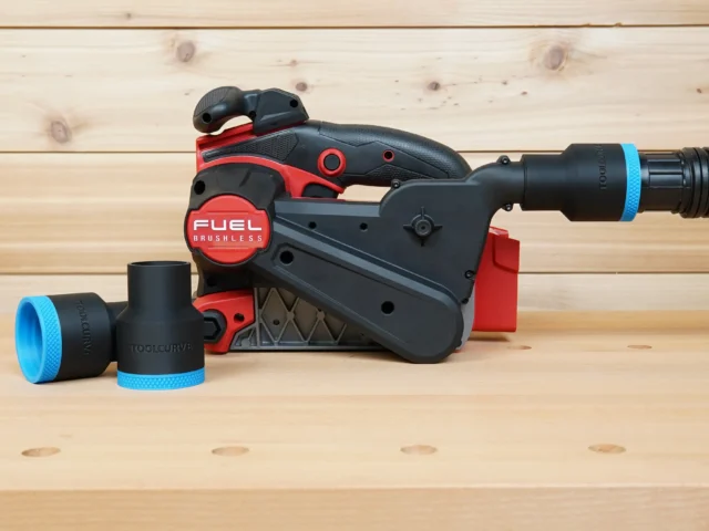 Black ToolCurve 1-7/8 inch hose adapter with blue band on a Milwaukee M18 belt sander, second adapter beside it