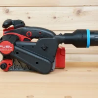 Black ToolCurve 2-1/2 inch hose adapter with blue ring joining a vacuum hose to a Milwaukee M18 belt sander dust port